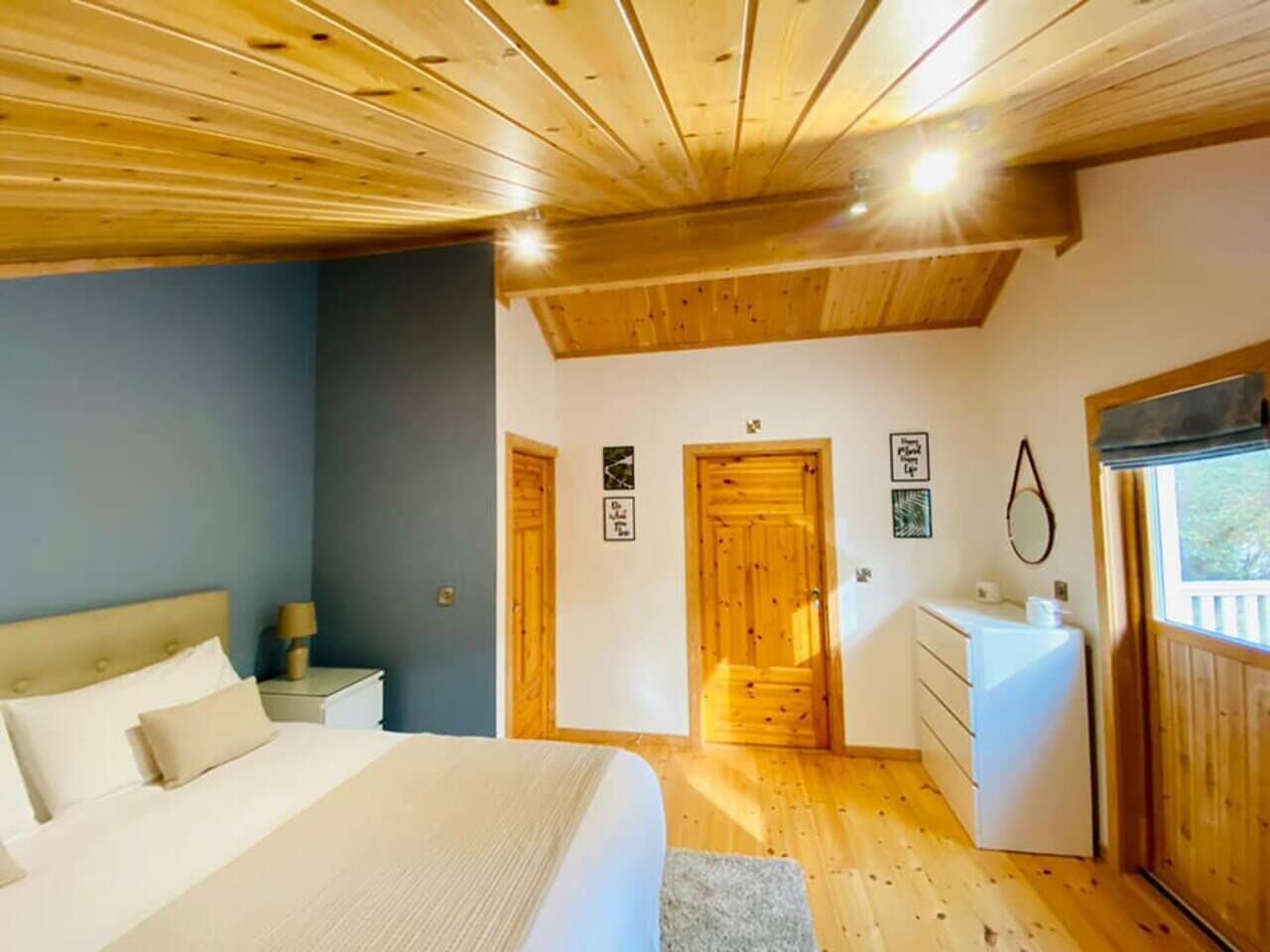 A bedroom with a bed, nightstand, dresser, and a window.
