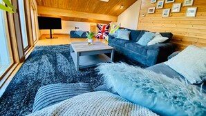 Un salon chaleureux avec un plafond en bois, un canapé, une table basse et un téléviseur.