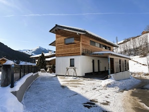 A two-story wooden house with a covered porch and a snow-covered driveway. - Pantera - SKI IN SKI OUT by Interhome (Saalbach-Hinterglemm)