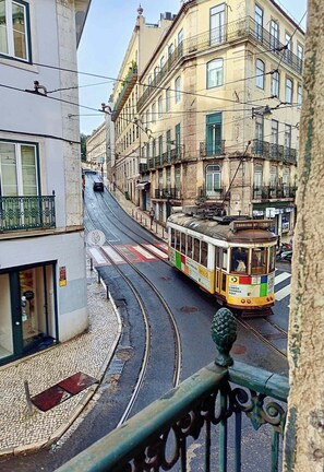 A tram on a curved street in a city with buildings on both sides. - S o Bento Tramview Residence (Lisbon)