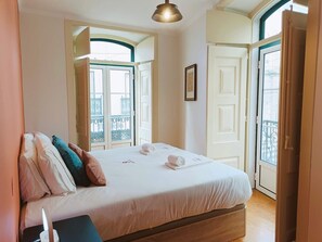 A hotel room with a bed, a bedside table, a lamp, a window with a view of a balcony, and a door. - S o Bento Tramview Residence (Lisbon)