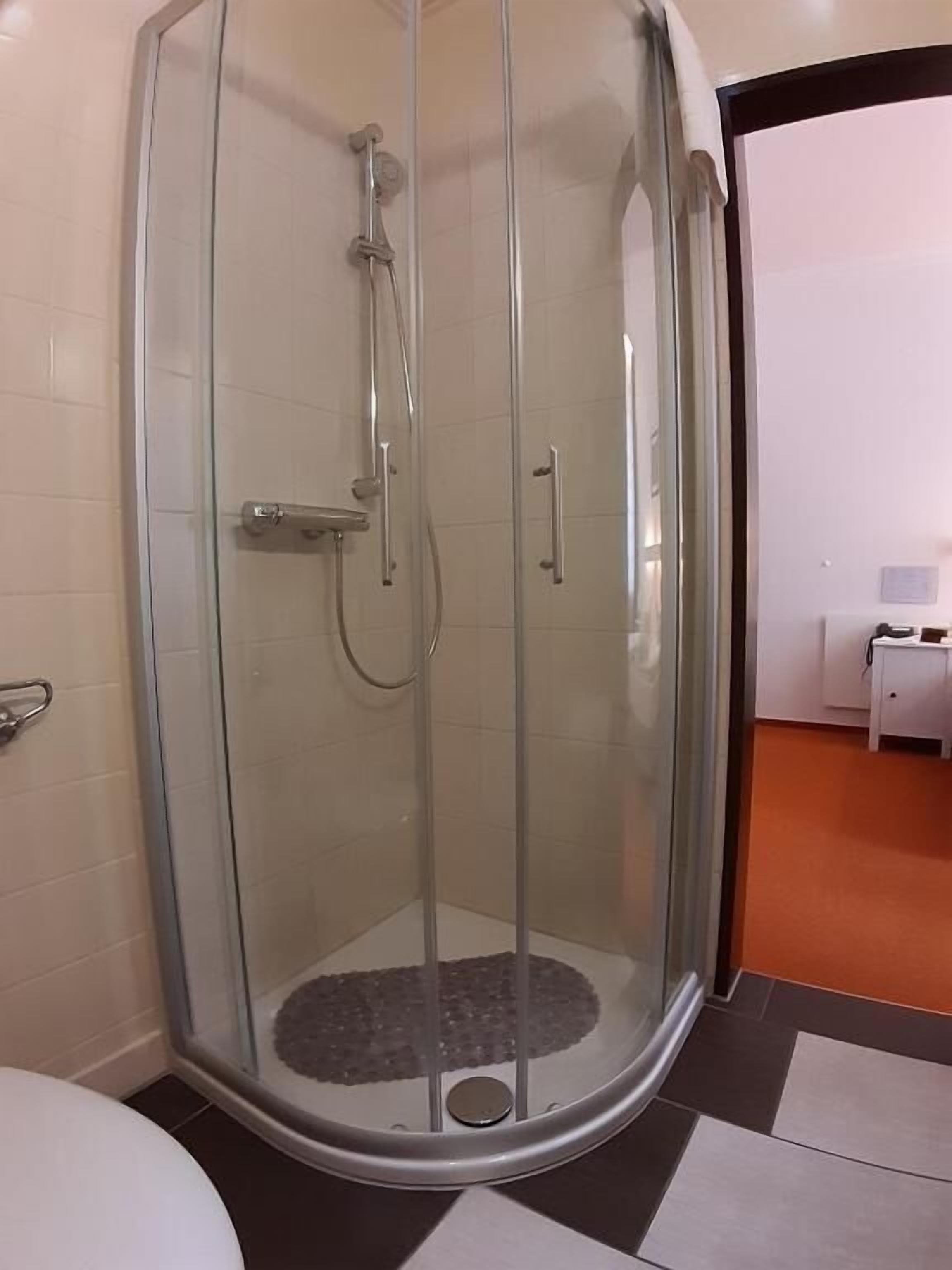 Eine begehbare Dusche mit Glaswänden, einer Handbrause und einem Handtuchhahn.