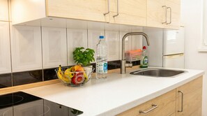 A kitchen with white cabinets, a stainless steel sink, a fruit bowl with bananas and apples, a water bottle, and a dish soap bottle. - Central Vecindario Apartment · 10 min from Airport · Fast WiFi (Vecindario)