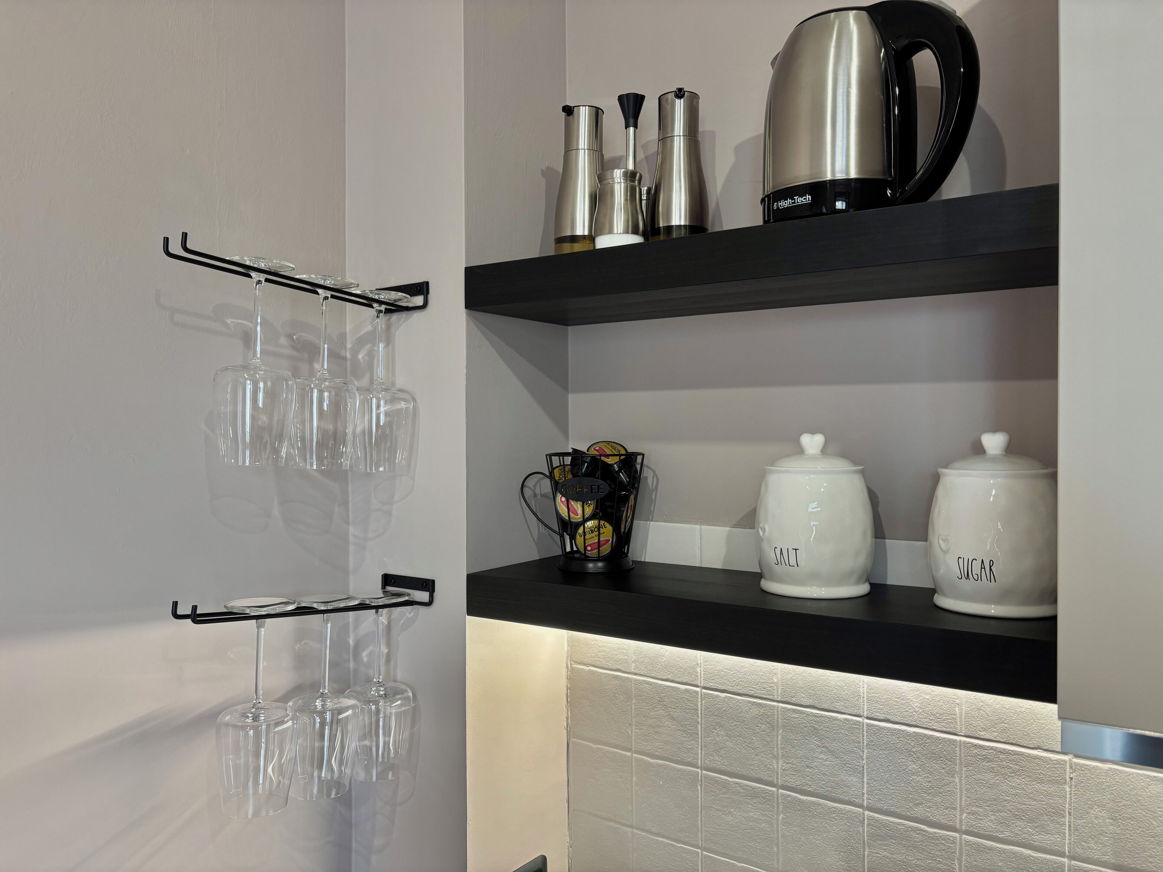 A kitchen with a black countertop, a wine rack, and storage jars labeled 'SALT' and 'SUGAR'.