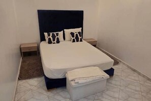 A neatly made bed with a dark headboard, two bedside tables, and a small bedside drawer. - Villa Eden - Elegance, comfort & serenity for the whole family (Douar Moulay Abbas)