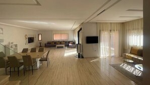 Ein geräumiger Wohnbereich mit Esstisch, Sofa und Fernseher.
