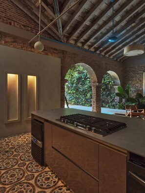 Una cocina moderna con una isla central, lavavajillas empotrado y vistas a un jardín exuberante a través de un ventanal arqueado.