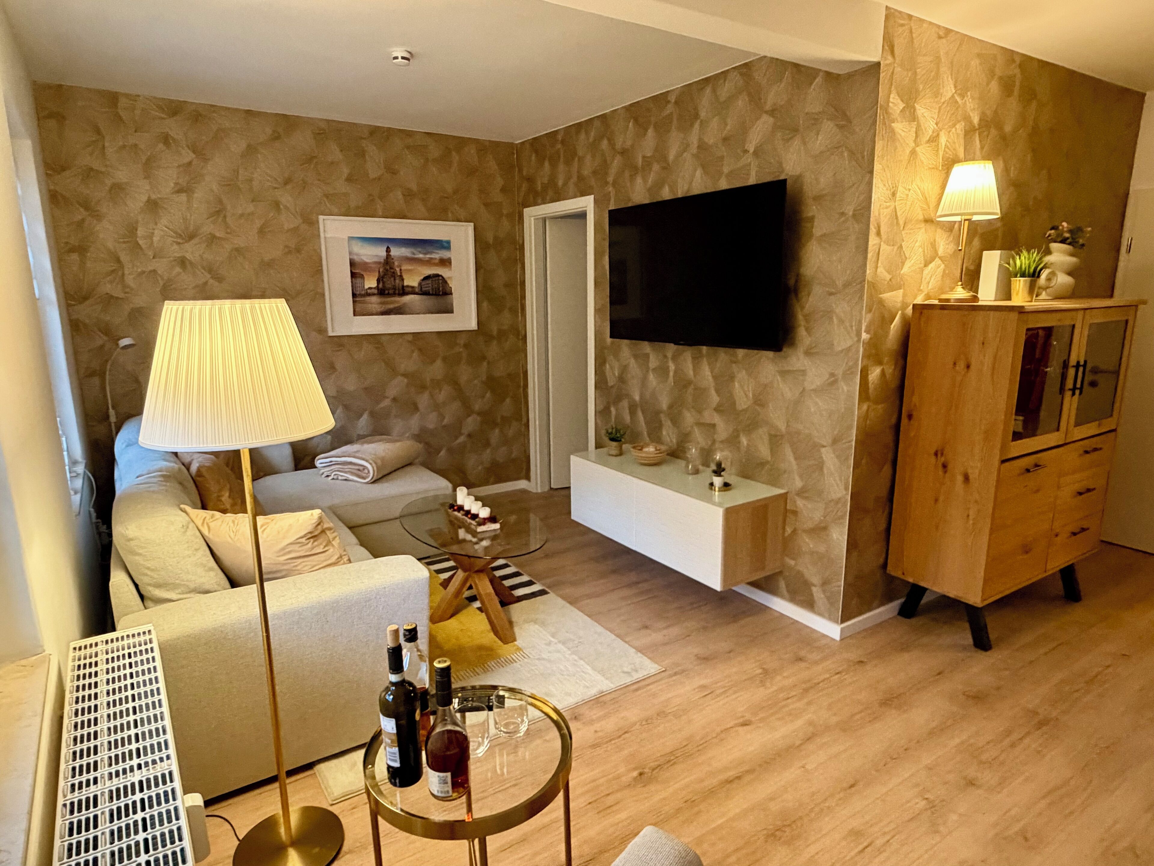 Ein modernes Wohnzimmer mit einer Couch, einem Couchtisch, einem an der Wand montierten Fernseher und einer Holzkommode.