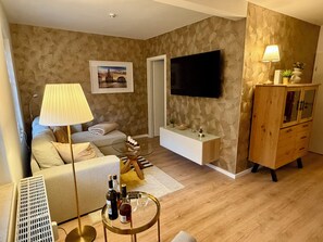 A modern living room with a sofa, a coffee table, a TV mounted on the wall, and a wooden cabinet. - Modern and stylish vacation apartment Kathy - parking, sauna, balcony (Bad Schandau)