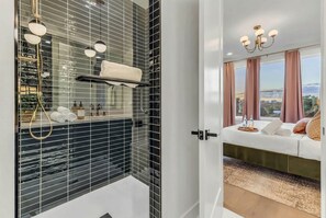 Ein modernes Badezimmer mit einer Duschkabine aus Glas, einem Handtuchhalter und einem Waschtisch mit Toilettenartikeln.