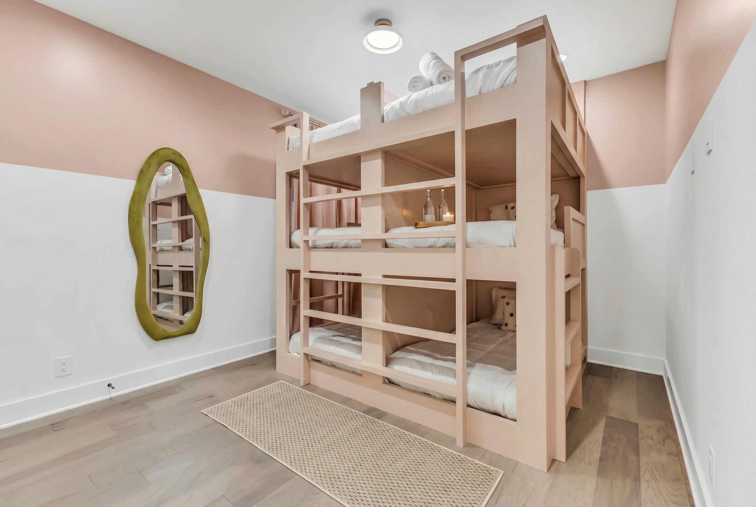 A bunk bed with storage shelves, a woven rug, and a mirror on the wall.