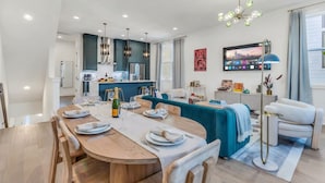 A modern kitchen with a dining area, a sofa, and a TV on the wall. - Hip Rooftop Deck Game Room in Downtown Nashville (Nashville)