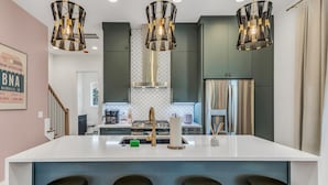 A modern kitchen with a central island, stainless steel appliances, and pendant lighting. - Hip Rooftop Deck Game Room in Downtown Nashville (Nashville)