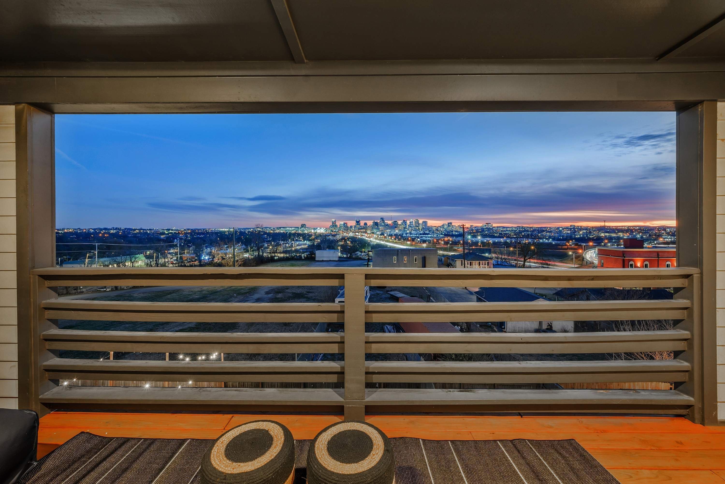 Ein Balkon mit Blick auf eine Stadtlandschaft im Abendlicht.