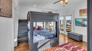 A modern bedroom with a bunk bed, a ceiling fan, and a city view. - Game Room Balcony Backyard Near Downtown Nash (Nashville)