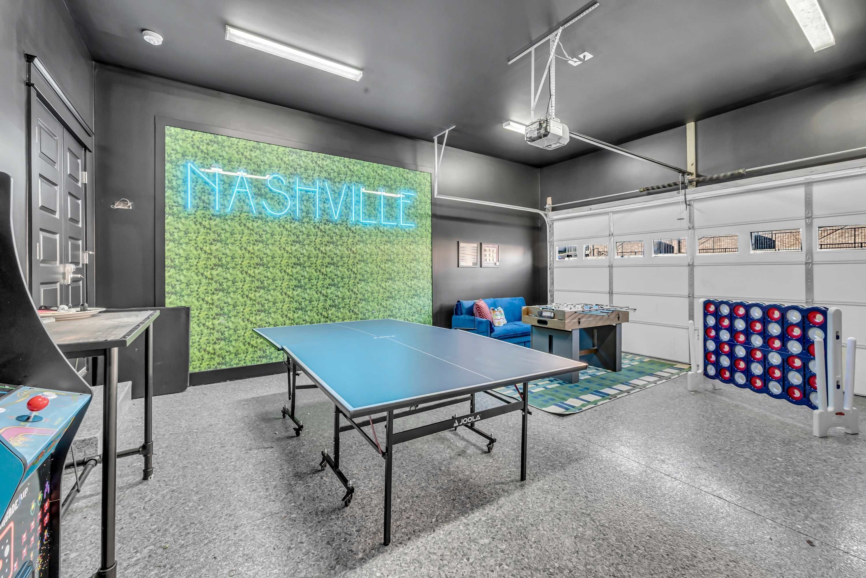 Un espace intérieur moderne avec une table de ping-pong, un néon lumineux sur lequel on peut lire « NASHVILLE », et un projecteur fixé au plafond.