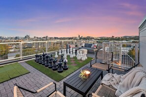 A rooftop terrace with a chessboard, seating area, and a city view at sunset. - Luxury Retreat Double Rooftop Deck Game Room (Nashville)