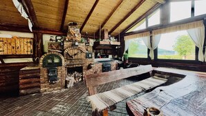 A rustic wooden interior with a stone fireplace, a bench, and a rustic dining table. - Awesome 6-bedroom cabin in adorable Darmanesti perfect for group getaways (Dărmănești.)