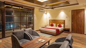 Ein modernes Hotelzimmer mit einem großen Bett, zwei Sesseln, einem Holztisch und einem Deckenventilator.