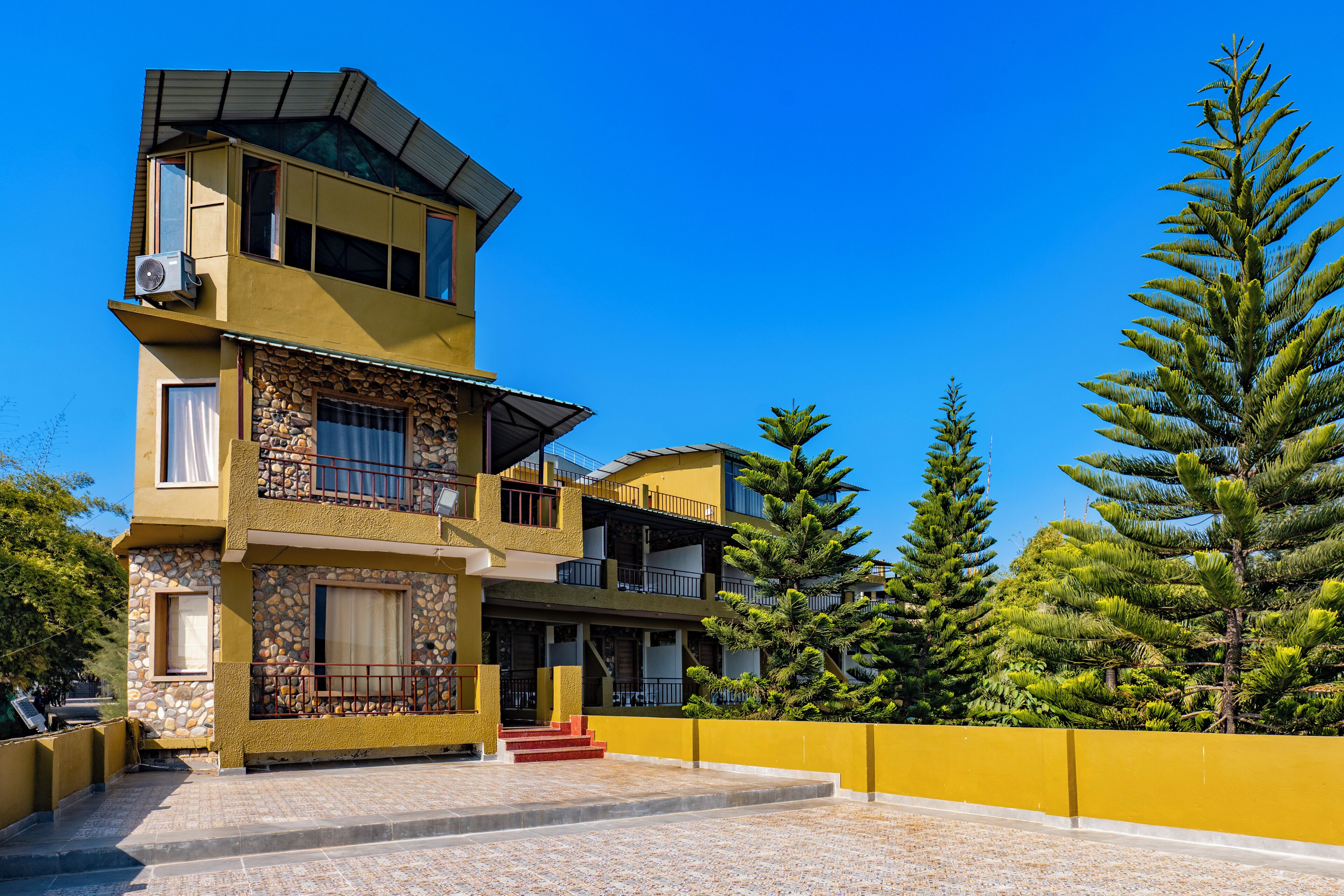 A multi-story building with a stone facade, balconies, and a clear blue sky.