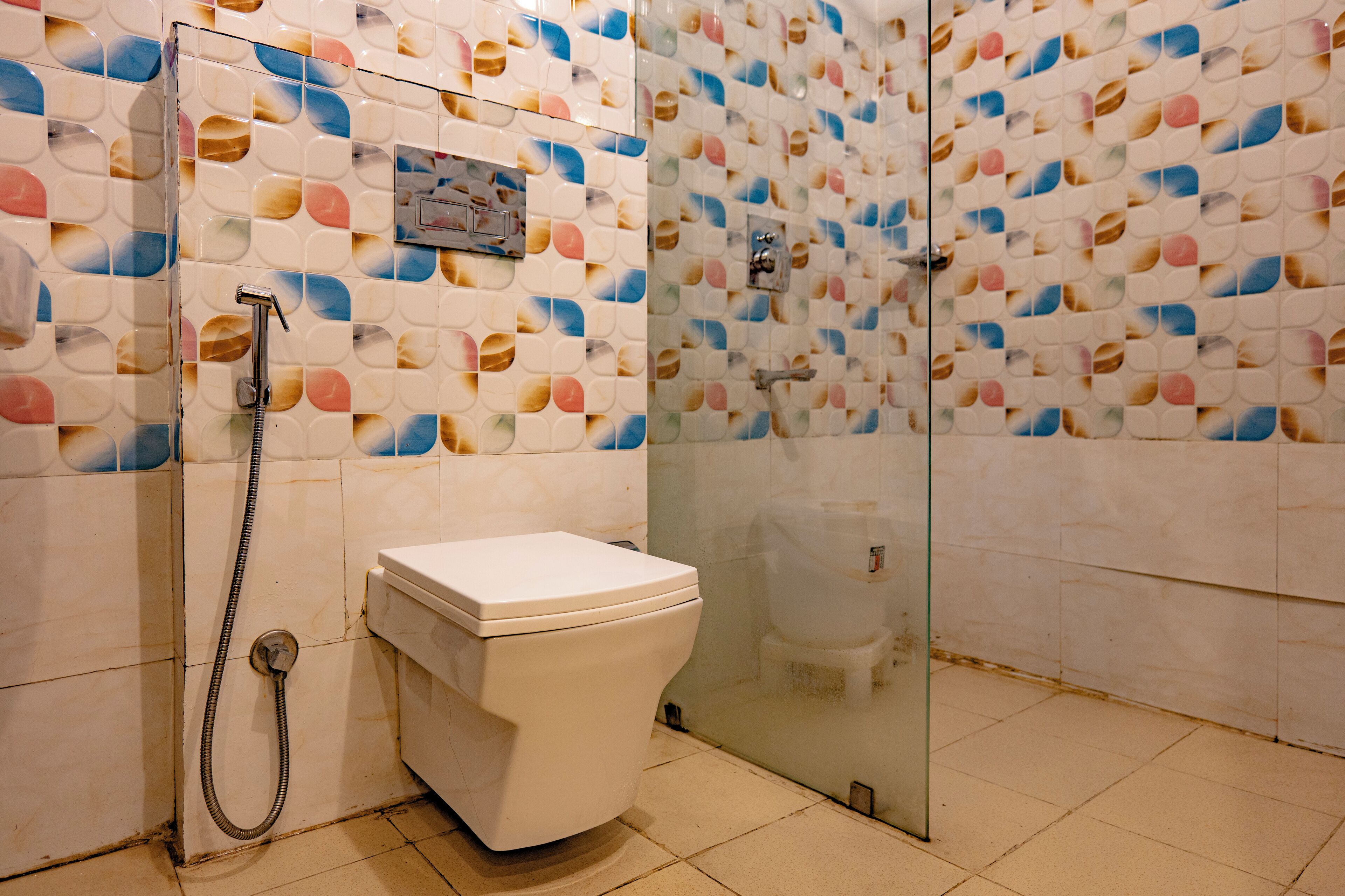 A bathroom with a toilet, shower, and glass-enclosed shower stall.
