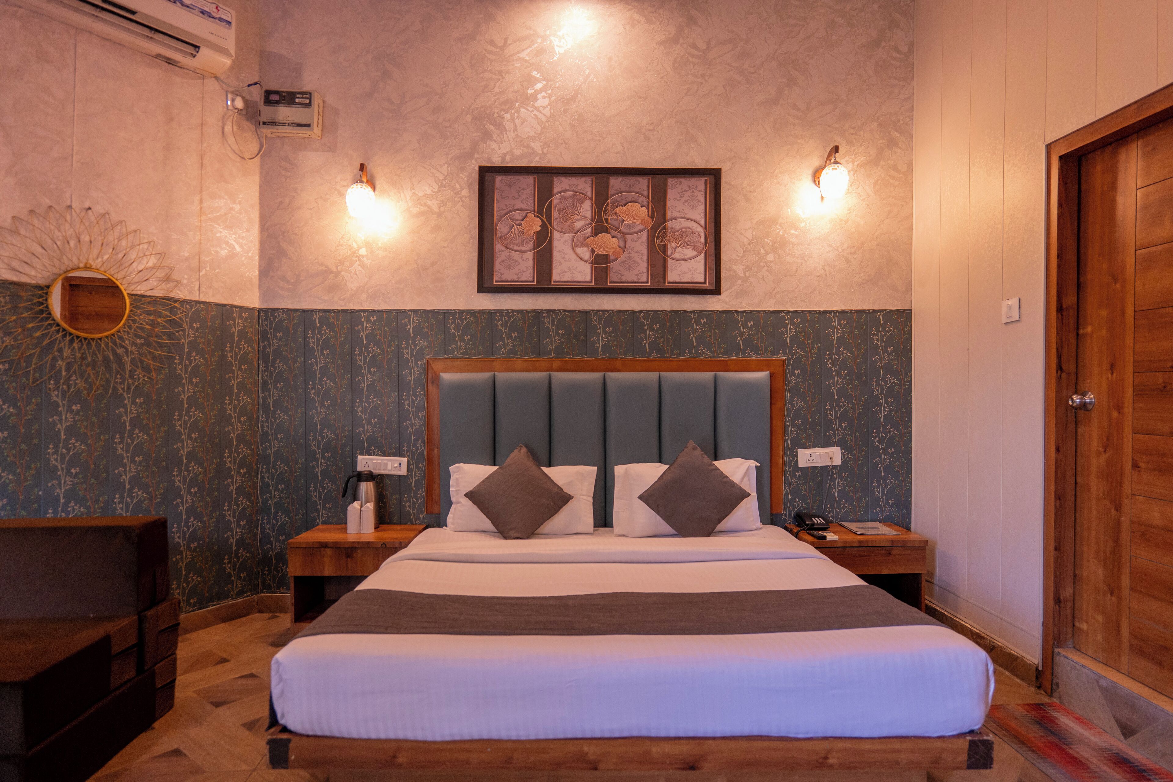 Een hotelkamer met een groot bed, twee nachtkastjes, een houten deur en een luchtverkoeler aan de muur.