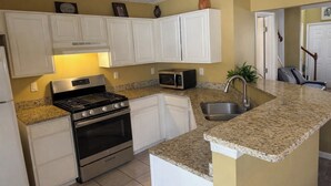 A kitchen with white cabinets, a stainless steel stove, a microwave, and a granite countertop. - The Red Door Condo ATL managed by The REZORT Group (College Park)