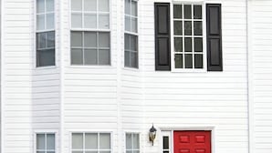 A two-story white building with a red door, multiple windows, and a black awning. - The Red Door Condo ATL managed by The REZORT Group (College Park)