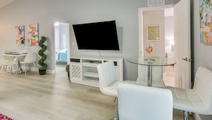 A modern living room with a flat-screen TV, white furniture, and a glass table. - Canal-front Oasis! Port Charlotte Condo w/ Lanai (Port Charlotte)