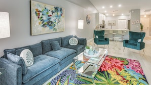 A modern living room with a blue sofa, teal chairs, and a colorful rug. - Canal-front Oasis! Port Charlotte Condo w/ Lanai (Port Charlotte)