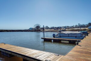 Un muelle de madera se adentra en aguas tranquilas, con un barco cubierto amarrado al final.
