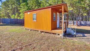 Una petita cabana de fusta amb un porxo, una porta i una finestra.