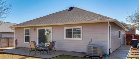 A single-story house with a covered patio, a small table and chairs, and an air conditioning unit.