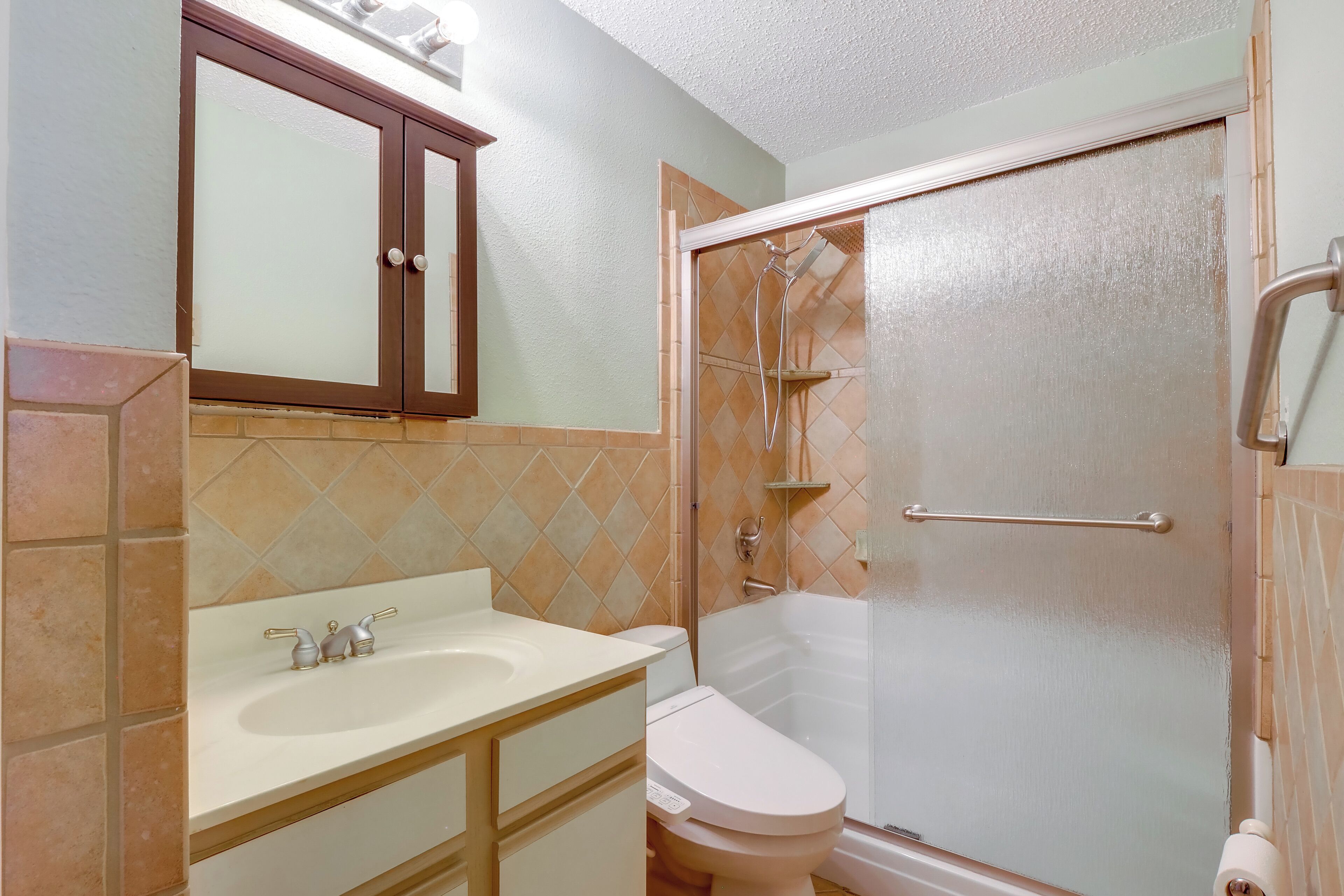 A bathroom with a toilet, sink, and shower area.