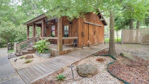 Une cabane en bois dotée d’un porche, d’un escalier et d’un jardin agrémenté de rochers et de plantes.