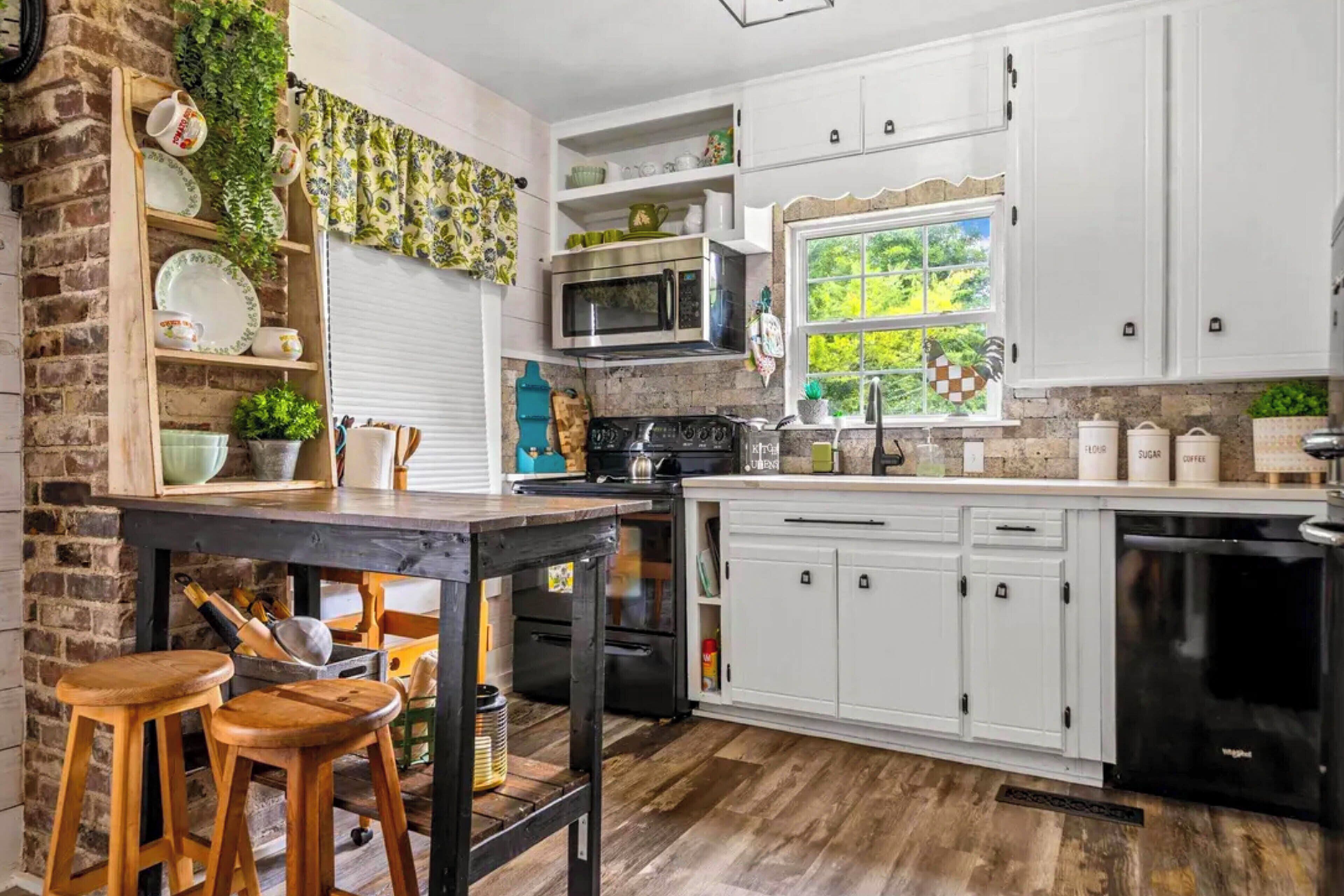 A kitchen with white cabinets, a black stove, and a wooden table with stools.