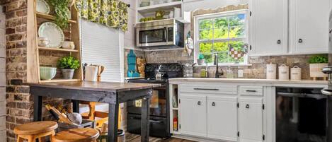 A kitchen with white cabinets, a black stove, and a wooden table with stools.