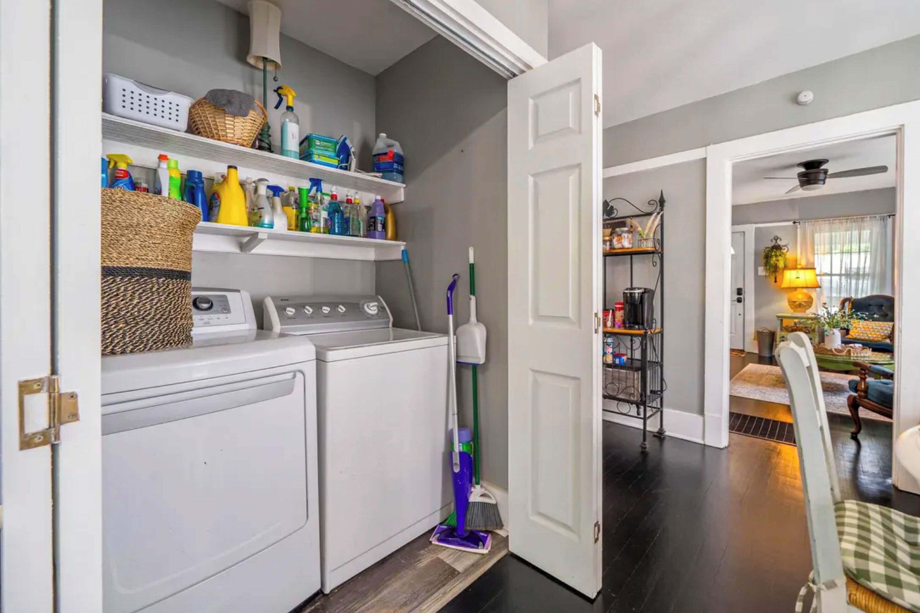 A laundry area with a washing machine, dryer, and shelves with cleaning supplies.