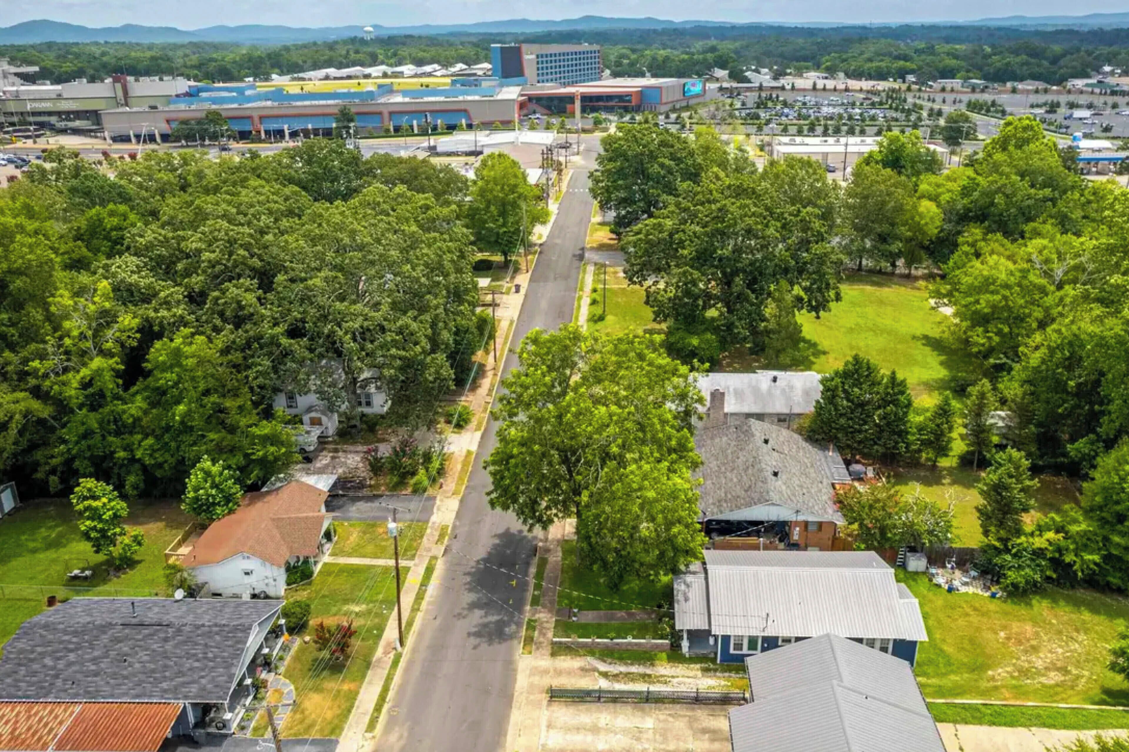 Vue aérienne d’un quartier résidentiel avec des maisons, une rue principale et un grand bâtiment en arrière-plan.