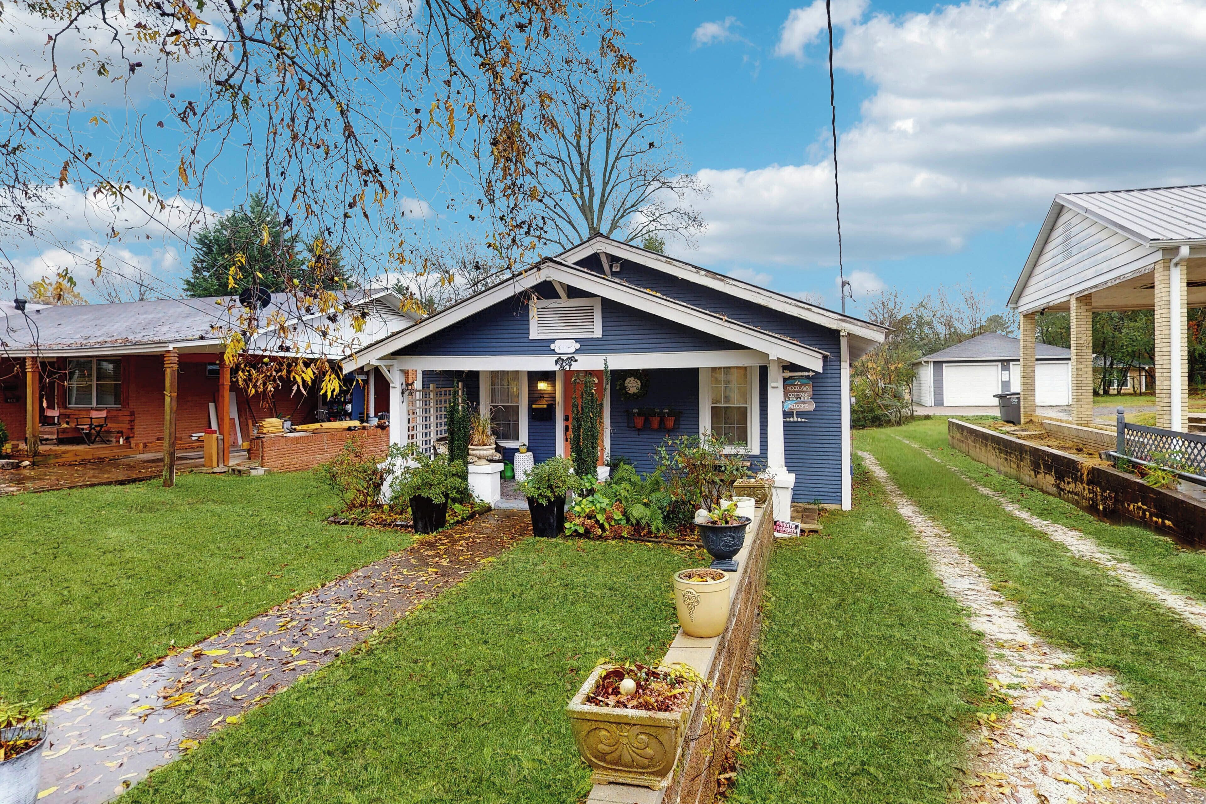 A blue house with a porch, surrounded by a well-maintained lawn and potted plants.