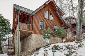 A log cabin with a stone foundation, a wooden deck, and a staircase leading to the entrance. - Family Haven w/ Hot Tub! 5 Mi to Dtwn Pigeon Forge (Sevierville)