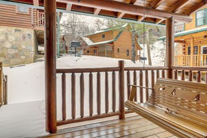 A wooden deck with a bench, a stone wall, and a snow-covered ground. - Family Haven w/ Hot Tub! 5 Mi to Dtwn Pigeon Forge (Sevierville)