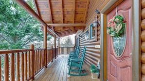A wooden deck with rocking chairs, a wooden door with a wreath, and a view of trees. - Family Haven w/ Hot Tub! 5 Mi to Dtwn Pigeon Forge (Sevierville)