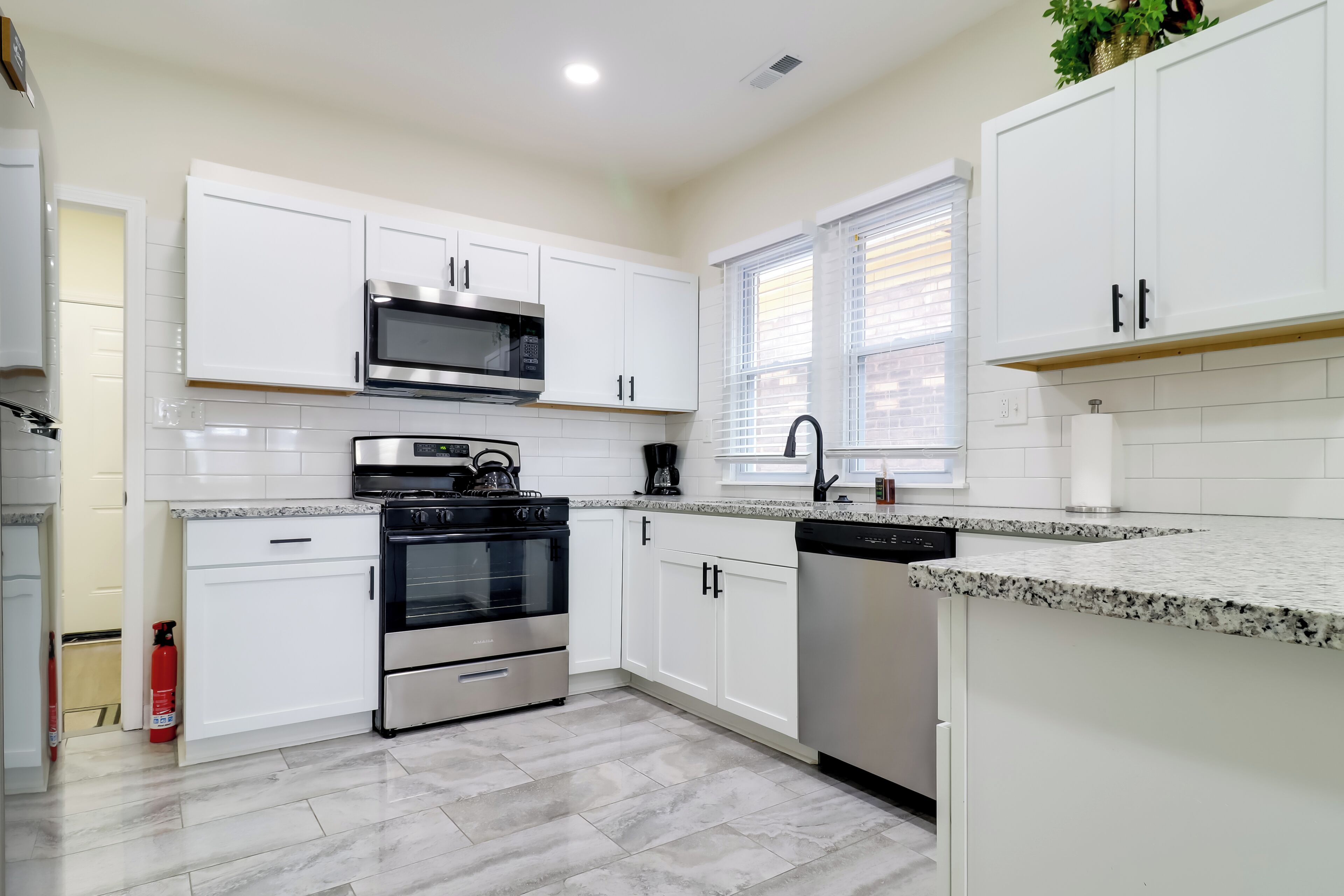 Una cocina moderna con armarios blancos, electrodomésticos de acero inoxidable y encimera de granito.