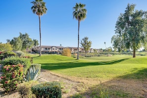 A golf course with palm trees, a well-maintained lawn, and a building in the background. - Golf Course Views! Relaxing & Convenient Mesa Unit (Mesa)