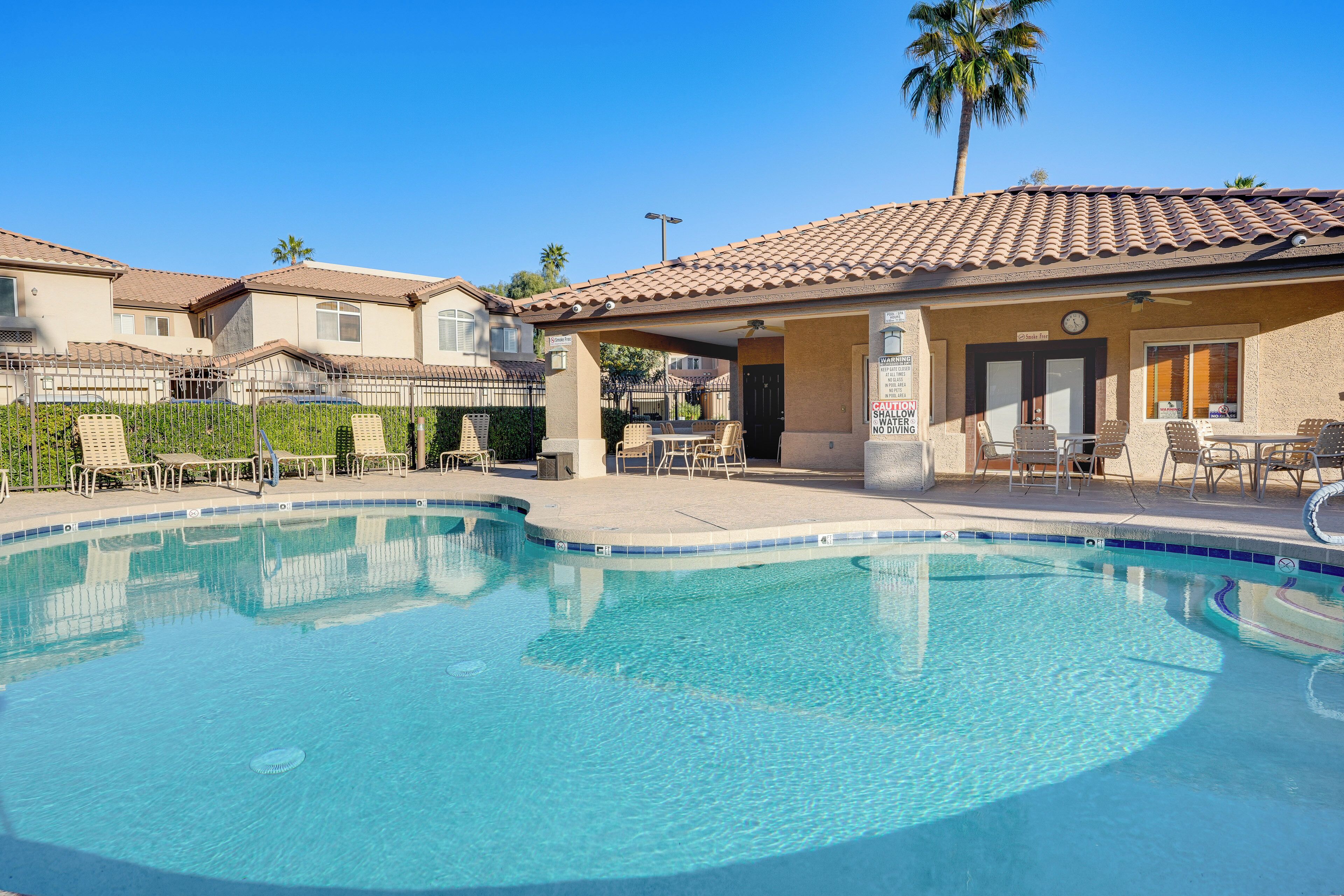 A swimming pool with lounge chairs and a covered patio area.