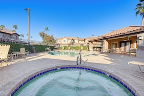 A swimming pool with a tiled edge, lounge chairs, and a building with a tiled roof in the background. - Golf Course Views! Relaxing & Convenient Mesa Unit (Mesa)
