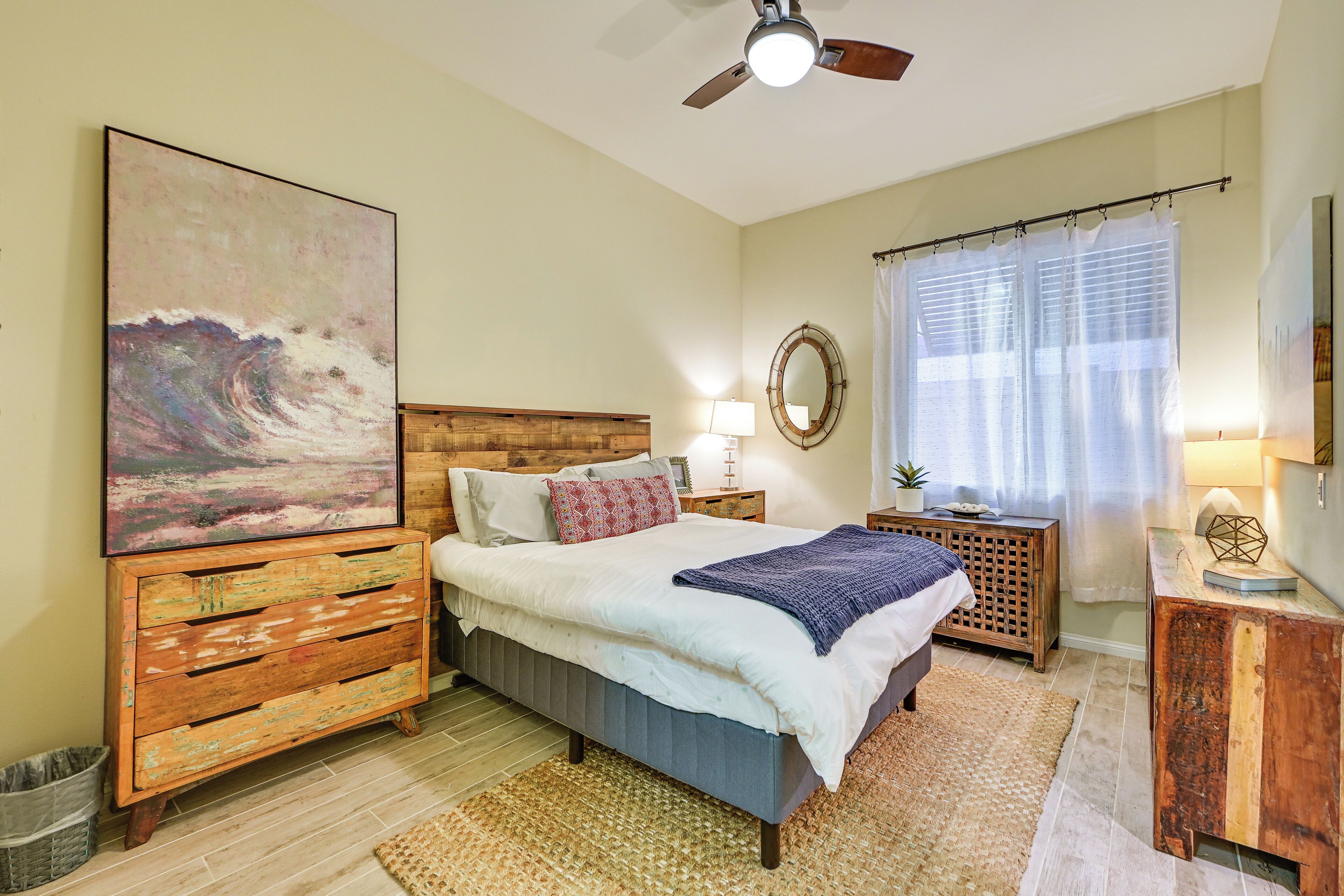 Une chambre à coucher avec un lit, une commode en bois et des œuvres d’art.