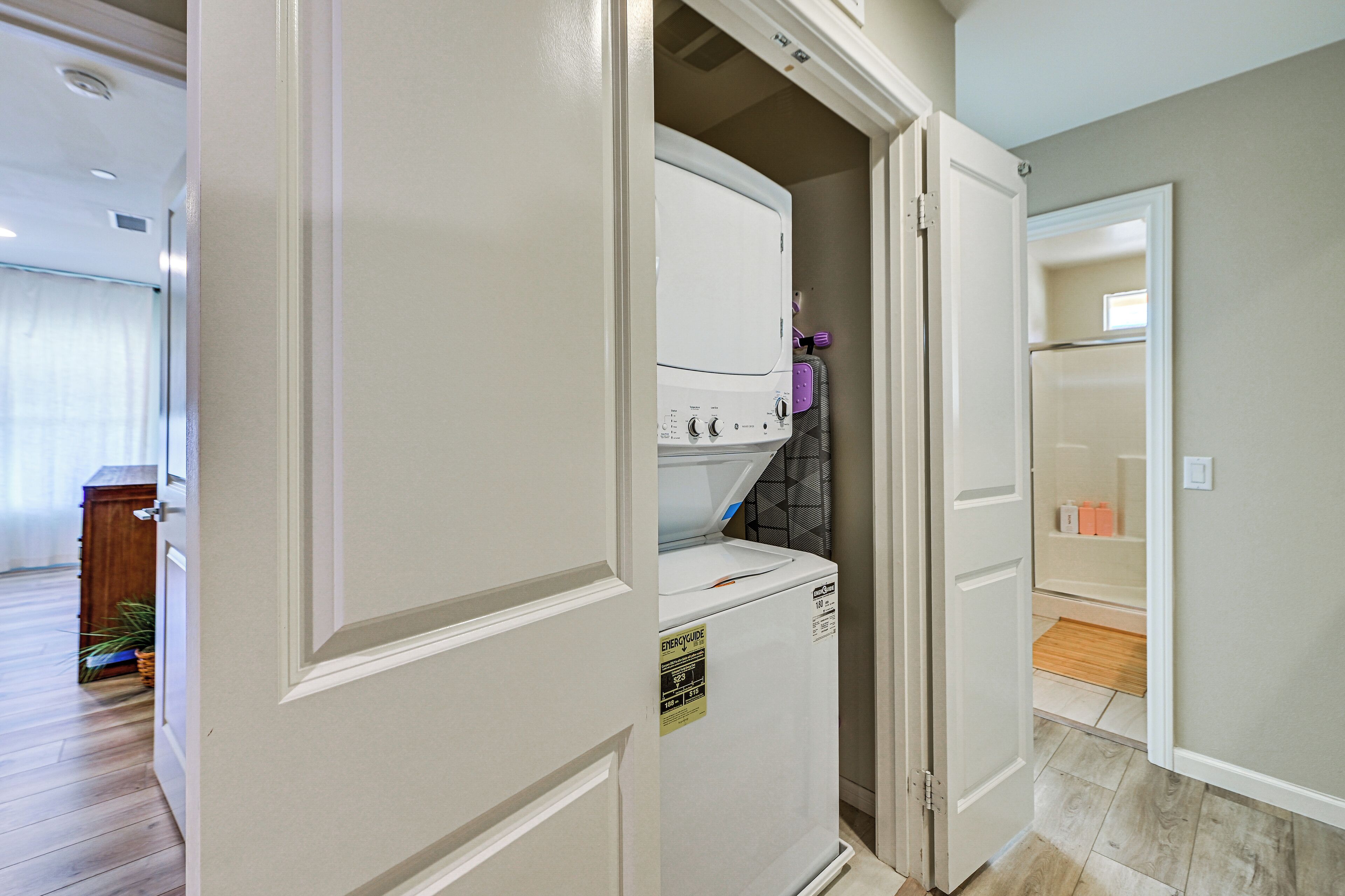 A laundry room with a white washer and dryer, a purple appliance, and a door leading to another room.