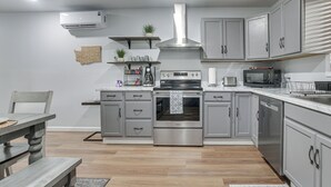 A modern kitchen with grey cabinets, a stainless steel range hood, a built-in oven, a microwave, and a coffee maker. - Brand-new Sequim Escape: A/c, Fire Pit, Grill (Sequim)